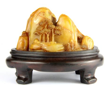 A fine Chinese carved pebble hardstone scholars seal of a mountain landscape on a carved hardwood stand, overall H. 8.5cm.