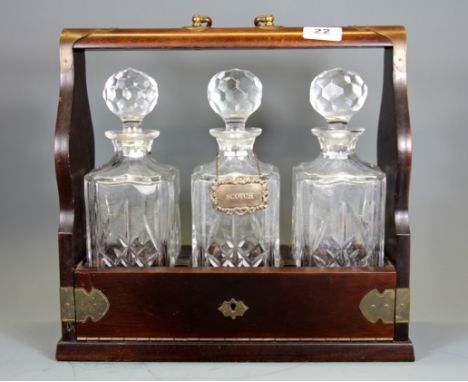 A mahogany three bottle tantalus, W. 35cm H. 34cm, together with a hallmarked silver scotch label.