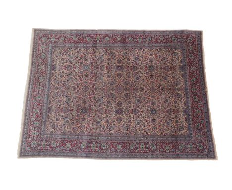 Kirman Carpet South Iran, circa 1950 The cream field with an all over design of vines and palmettes, enclosed by raspberry bo