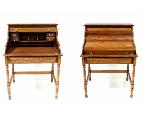 A reproduction oak roll-top desk of small proportions, the tambour shutter enclosing pigeonholes and drawers above single fri