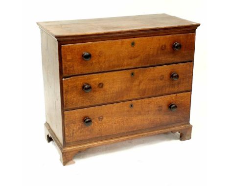 An early 19th century tiger fleck oak chest of drawers with shaped top above three long drawers and raised on bracket feet, w
