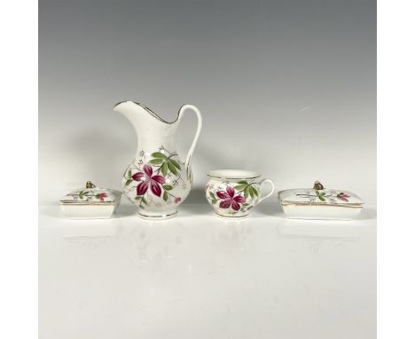 A charming set of four white items adorned with pink flowers, green foliage, and gilded accents, including a pitcher, a round