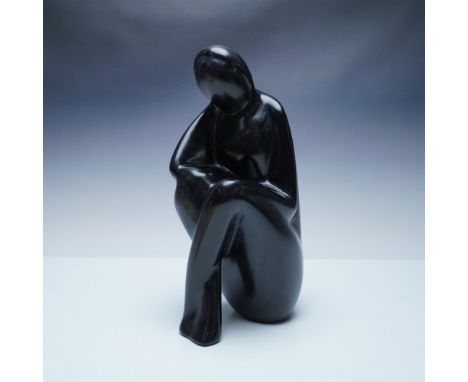 A striking hand-carved black stone sculpture from Kenya, depicting a contemplative seated figure with a smooth, minimalist de