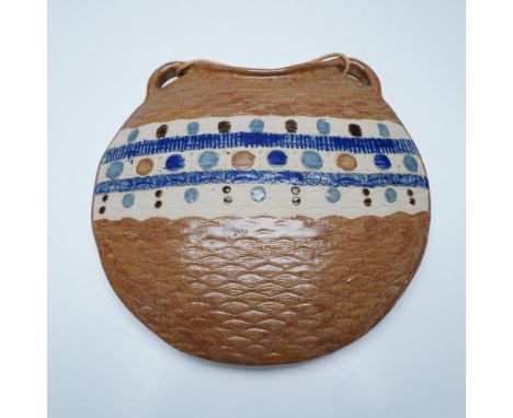 Handcrafted ceramic wall pocket with a textured surface and intricate painted details in blue, brown, and cream tones. The pi