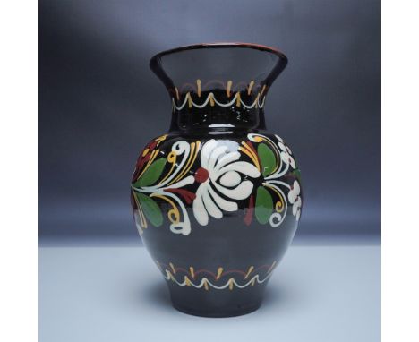 This hand-painted ceramic vase features a rich, dark glaze adorned with vibrant floral motifs in white, red, green, and yello