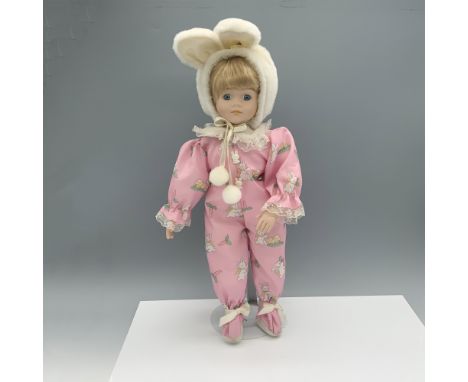 Charming figure of a child in a pink onesie with bunnies on it and a hat with bunny ears. Metal stand included. Brinns backst