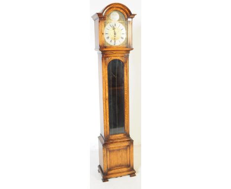An Art Deco style late 20th century oak grandfather clock. Having an arched hood with glazed front on hinged door. Repousse g