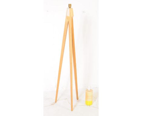 A contemporary beech wood floor standing standard lamp, alongside a smaller table side lamp. The lamp of elongated tripod for