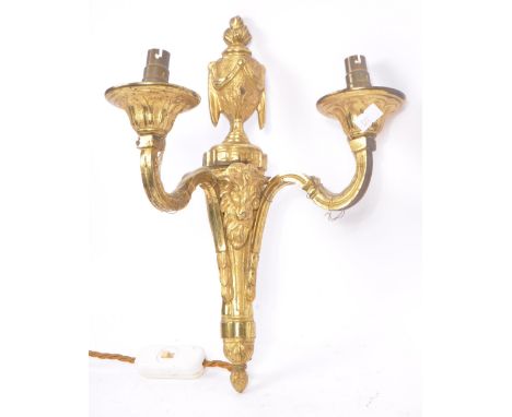 A brass gilded twin branch wall sconce lights with golden ram head to body and vase shaped finial with draped ribbon design a