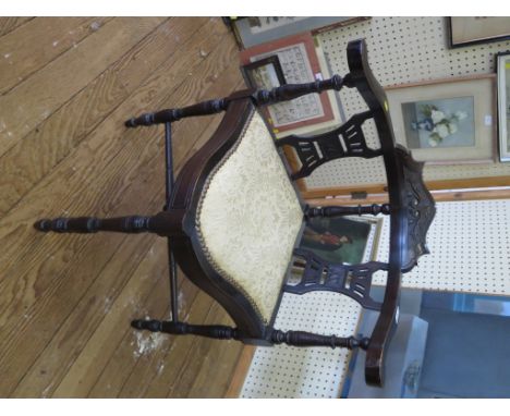 An ebonised corner chair with scroll carved top rail and ring turned legs