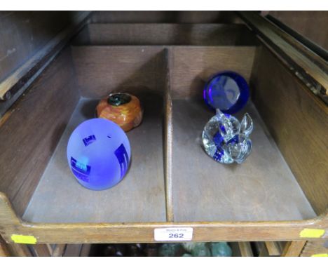 A collection of four glass paperweights including Caithness blue glass with etched dolphins, an unusual signed piece with dic