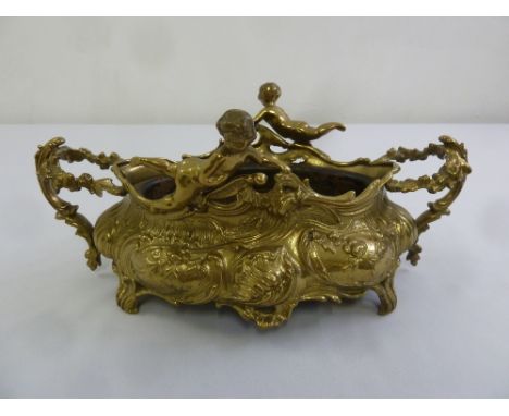 A gilt metal Art Nouveau style jardinière decorated with putti and flowers on four scroll legs