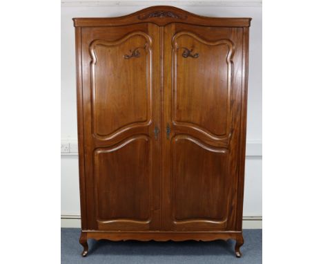 A French-style walnut twin-door wardrobe with a moulded cornice, having a fitted interior enclosed by a pair of fielded panel