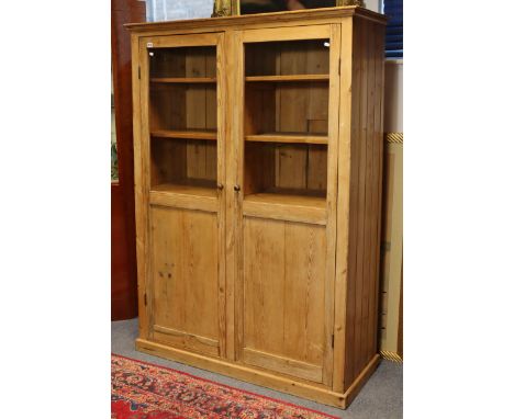 A pine hall cabinet, fitted ten shelves enclosed by a pair of glazed &amp; fielded panel doors, on plinth base, 50¾2 wide x 7