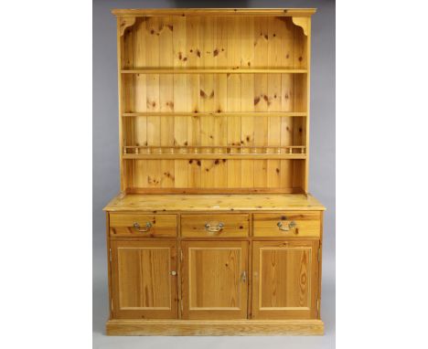 A pine dresser, the upper part with three open shelves &amp; panelled back ,the base fitted three frieze drawers above cupboa