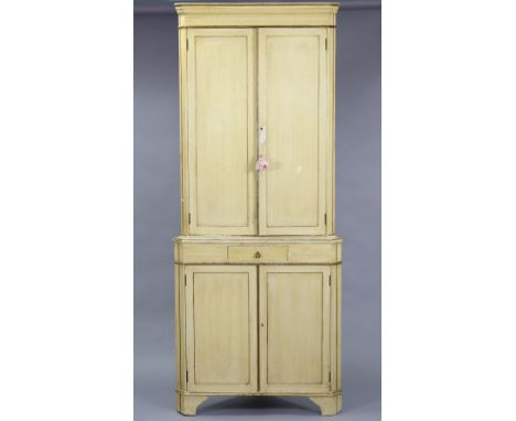 A 19th century cream painted two-tier standing corner cupboard, the upper part fitted two shaped shelves enclosed by pair of 