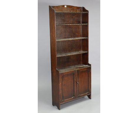 An early 20th century oak standing bookcase fitted five open shelves above a cupboard enclosed by pair of panel doors, 24¾” x