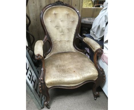 A Victorian button bach armchair with carved frame and raised on castors.
