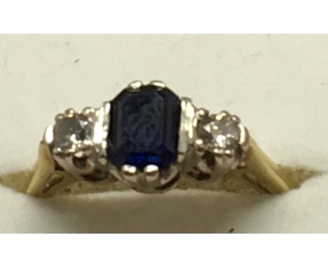 An 18ct gold ring set with a central sapphire flanked by diamonds, approx size K