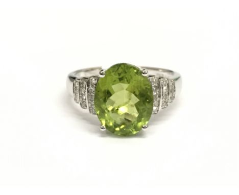 A 14ct white gold and diamond ring set with an oval cut peridot approximately 3.56ct. Diamonds approximately 0.25ct total wei