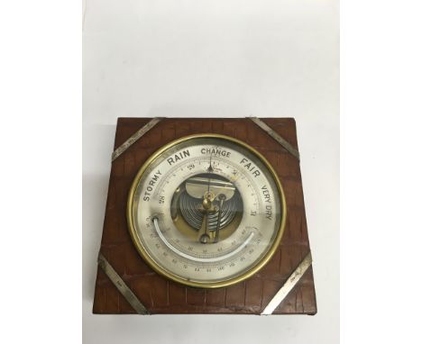A J.C Vickery brass barometer mounted in crocodile effect leather case with sliver mounts.Approx 22x22cm