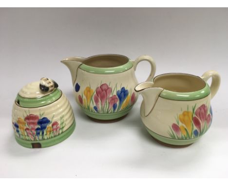 A three piece Clarice Cliff tea service in crocus pattern comprising two jugs and a sugar bowl.