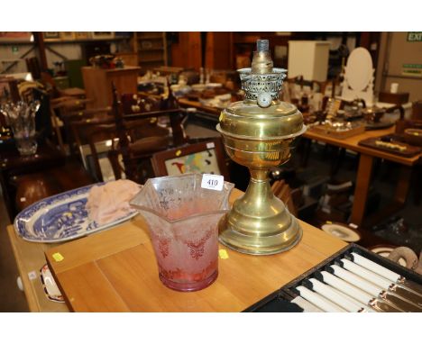 A Victorian brass oil lamp with red tinted etched shade