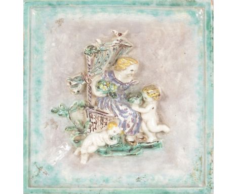 A FAIENCE SQUARE COLOURED TILE, a lady on a chair with two cupids in relief.  11ins x 10ins.