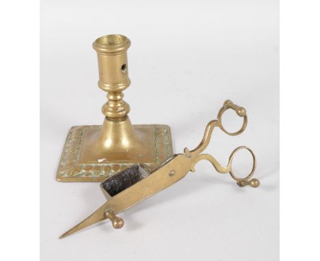 AN EARLY BRASS SQUARE BASE CANDLESTICK, 4ins high, and A CANDLE SNUFFER.