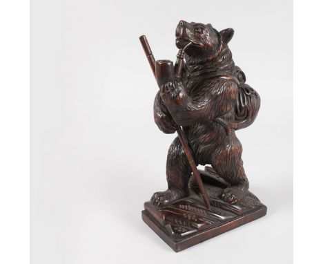 A GOOD CARVED WOOD BLACK FOREST STANDING CLIMBING BEAR with stick, pipe in his mouth and bag on his back. 12ins high.