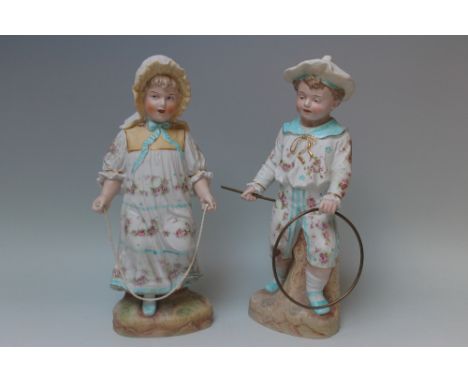 HEWBACH - A PAIR OF GERMAN BISQUE FIGURES, depicting a young girl in traditional dress with a skipping rope, and her companio