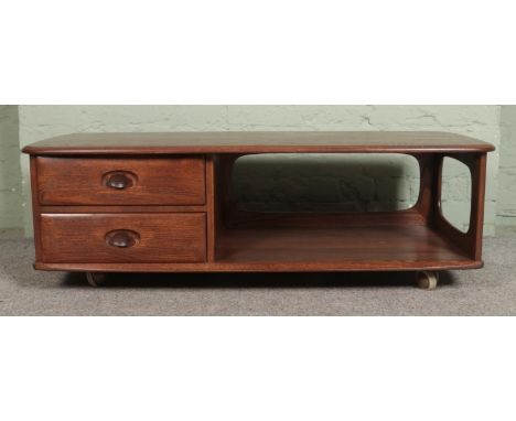 An Ercol Minerva elm coffee table, with partially open lower tier beside two drawers. Raised on casters. Height: 41cm, 125cm,