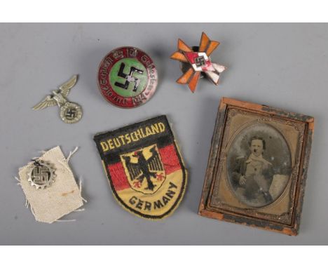 A collection of German WW2 period badges and patches with a small ambrotype.  