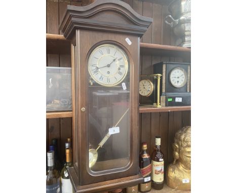 A wall clock with pendulum and key. 