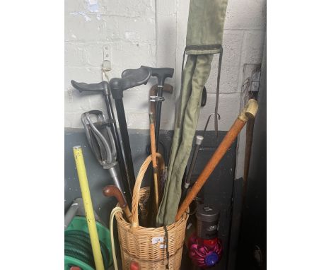 A wicker basket with walking sticks, a shooting stick and a fishing rod in bag. 