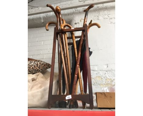 A stick stand ( no metal tray / base ) with walking sticks and umbrellas 