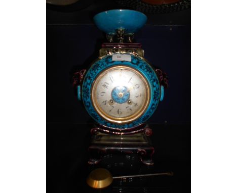 A French blue glazed Faience mantel clock with silvered dial and Arabic numerals, having grotesque mask handles surmounted wi