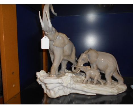 A Lladro group of three elephants on a rock formation  Restoration to the trunk of the stand alone elephant, chip to white ba