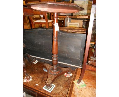 A Victorian mahogany octagonal lamp table raised in a ring turned column supports and tri-foil base