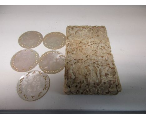 A 19th century ivory card case together with five mother of pearl counters, the rectangular sides of the case carved in low r