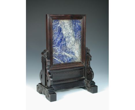 A lapis lazuli matrix table screen on carved hardwood stand, the rectangular panel carved in relief with pavilions amongst pi