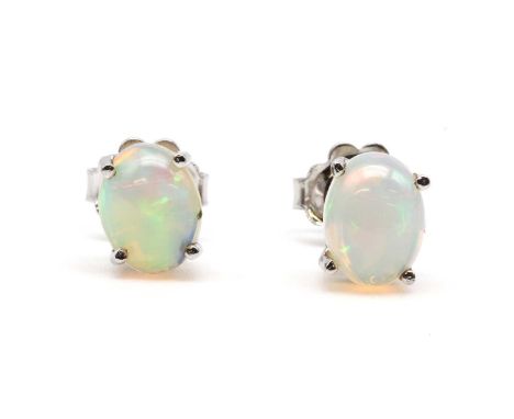 A pair of silver single stone opal stud earrings, with an oval cabochon opal, approximately 8 x 6mm, claw set to post and but