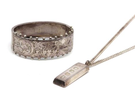 A Victorian sterling silver oval hinged bangle, with scrolling engraved decoration and hollow bead guards to the upper half, 