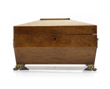 An oak tea caddy late 19th century, Regency style, sarcophagus form, with brass lion mask handles and paw feet, the interior 