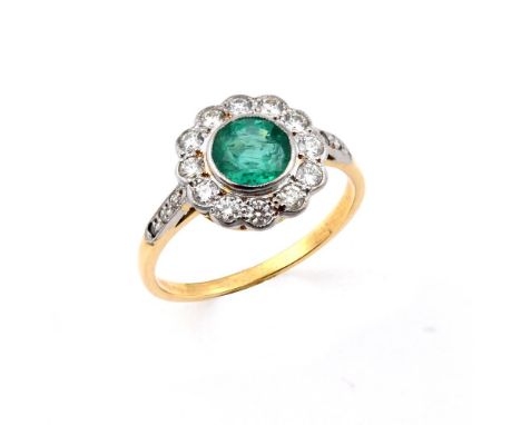 AN EMERALD AND DIAMOND CLUSTER RING. the circular-cut emerald is set within a surround of circular-cut diamonds, with further