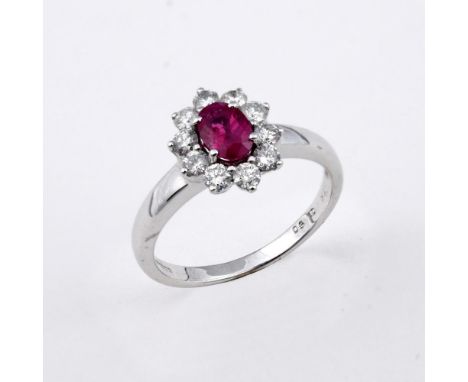 A RUBY AND DIAMOND CLUSTER RING. the oval-shaped ruby is set within a surround of ten round brilliant-cut diamonds in 18ct wh