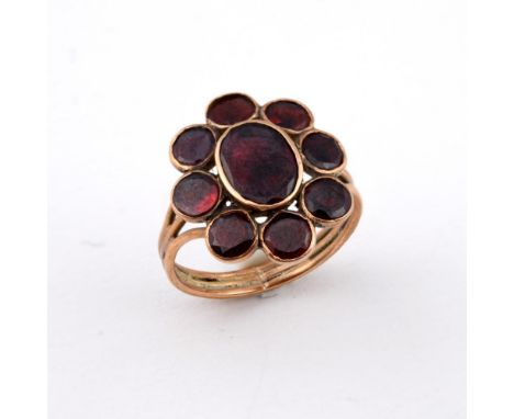 A GEORGIAN GARNET CLUSTER RING. the central oval-shaped garnet is set within a surround of circular-cut garnets in gold close