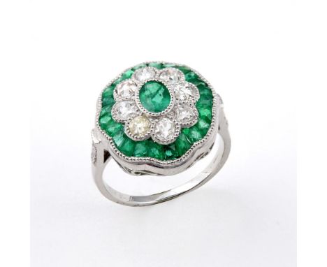 AN EMERALD AND DIAMOND CLUSTER RING. the central oval-shaped emerald is set within a surround of eight old-cut diamonds and a