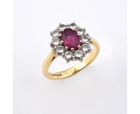 A RUBY AND DIAMOND CLUSTER RING. the oval-shaped ruby is set within a surround of ten circular-cut diamonds in 18ct gold. Siz