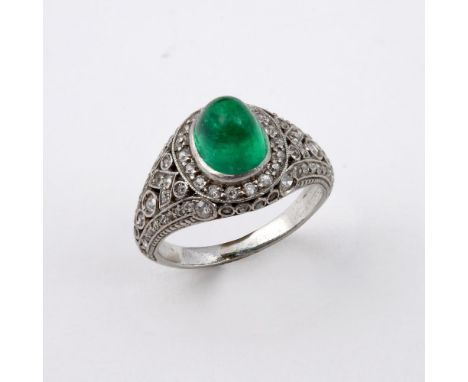 AN EMERALD &amp; DIAMOND CLUSTER RING. the oval-shaped cabochon emerald is set within a surround of circular-cut diamonds, wi